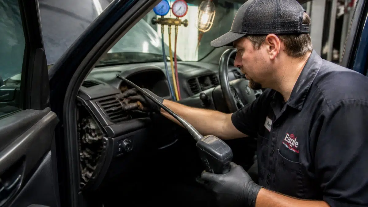 Technician using a leak detector to inspect the A/C evaporator and lines